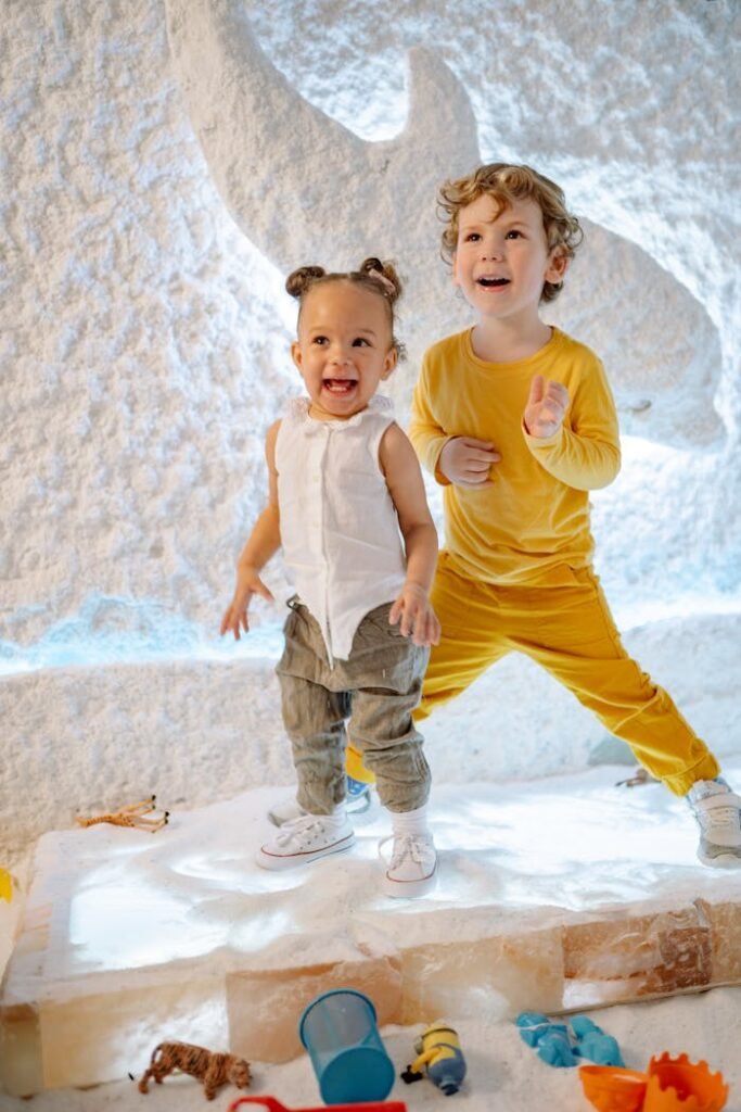 Two happy children playing in a salt room, enjoying toys and bright surroundings.